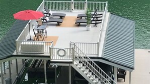 Une terrasse flottante avec des sièges extérieurs, un parasol rouge et un escalier menant à la terrasse supérieure.