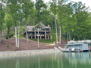 Situated on a lakeside property, this cabin offers a serene setting with a covered front deck and dock extending into the water.