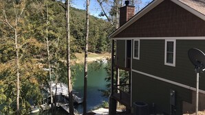 Une cabane avec un quai s’avançant dans un lac, entourée d’arbres.