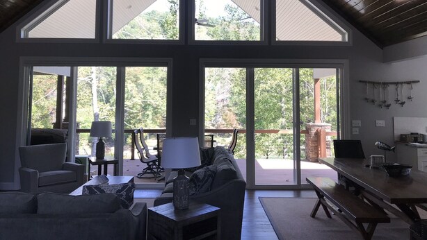 Un salon spacieux avec un plafond haut, de grandes fenêtres et une vue sur l’extérieur.
