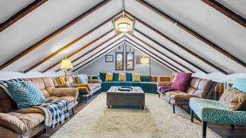 An attic room with a sloped ceiling, a central ottoman, two sofas, and a coffee table.