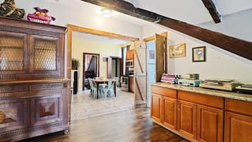 A kitchen with wooden cabinets, a dining area with chairs, and a staircase leading to another room.