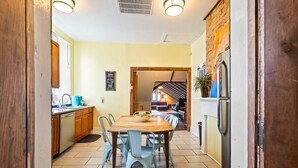 Een keuken met een eettafel, stoelen en een koelkast.