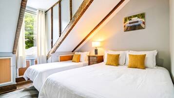 A hotel room with two beds, a wooden ceiling, a painting on the wall, and a window with curtains.