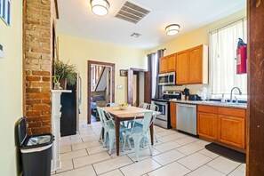 Una cocina con una mesa de comedor, sillas, un cubo de basura y un microondas.