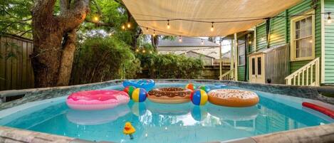 A hot tub with inflatable toys and a canopy overhead.