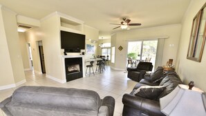 A spacious living room with a fireplace, a dining area, and a kitchen. - By Wharf Amphitheater and Sportsplex on the Orange Beach golf course. (Orange Beach)