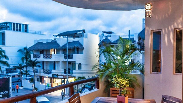 An outdoor dining area with a table and chairs, a potted plant, and a view of buildings in the background. - Great Location - Just steps from Mamitas Beach and Fifth Avenue ~ Special Rates  (Playa Del Carmen)