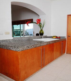 Eine Küche mit Granit Arbeitsplatten, Holzschränken, einer weißen Spüle und einem Fenster mit Blick.