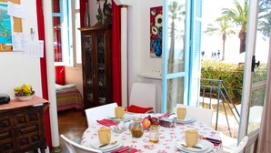 Un coin repas avec une table dressée pour quatre personnes, un meuble avec des portes en verre et une vue sur les palmiers à l’extérieur.