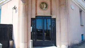 Une entrée d’immeuble avec une porte noire, des colonnes et une enseigne indiquant « BEL-AVVR ».