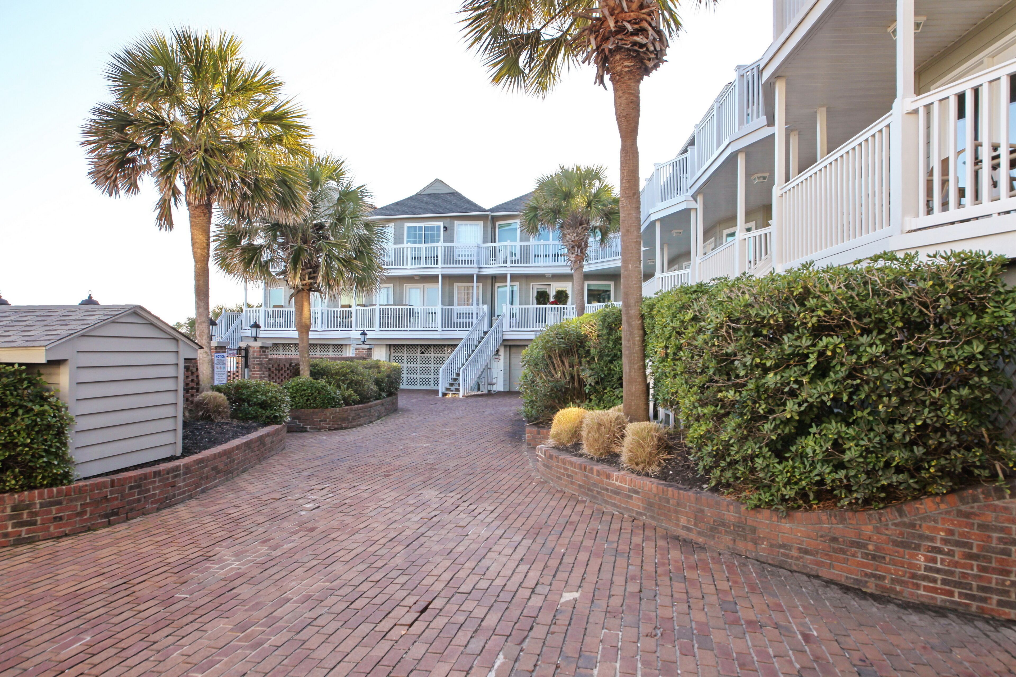 A brick-paved courtyard with a building featuring balconies and a covered walkway.