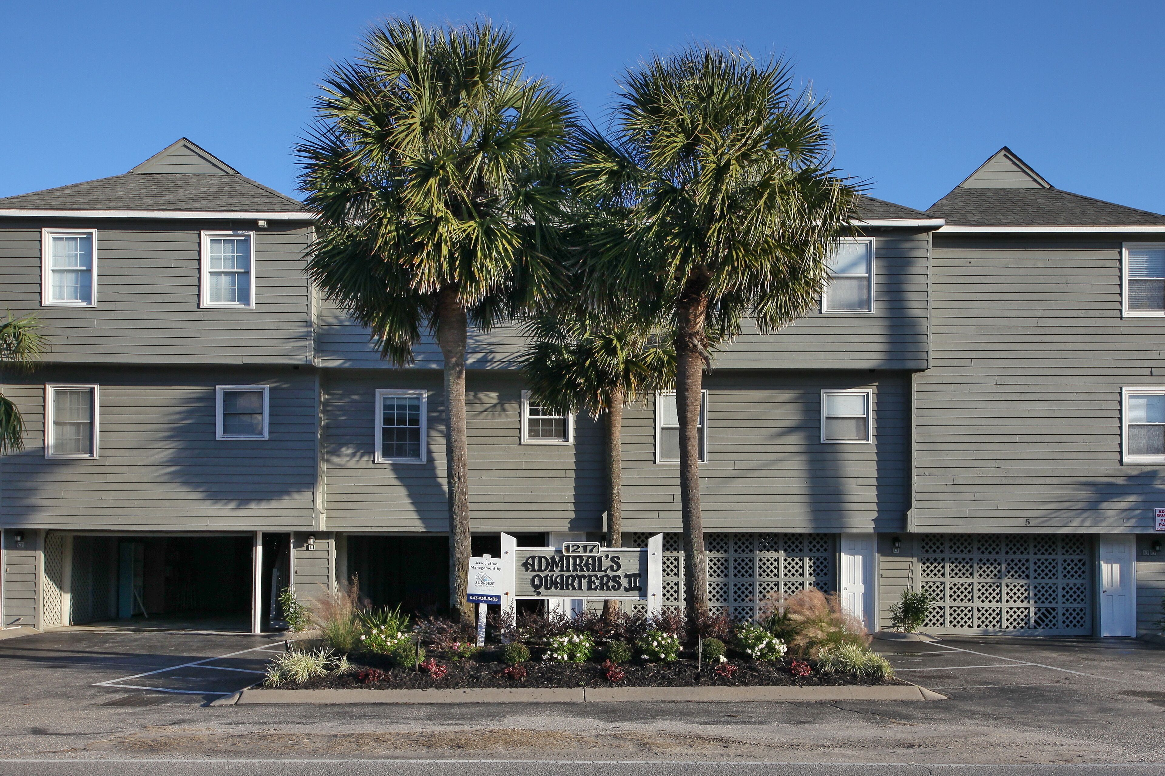 A two-story building with a sign for 'Admire's Guesthouse' and a parking lot in front.
