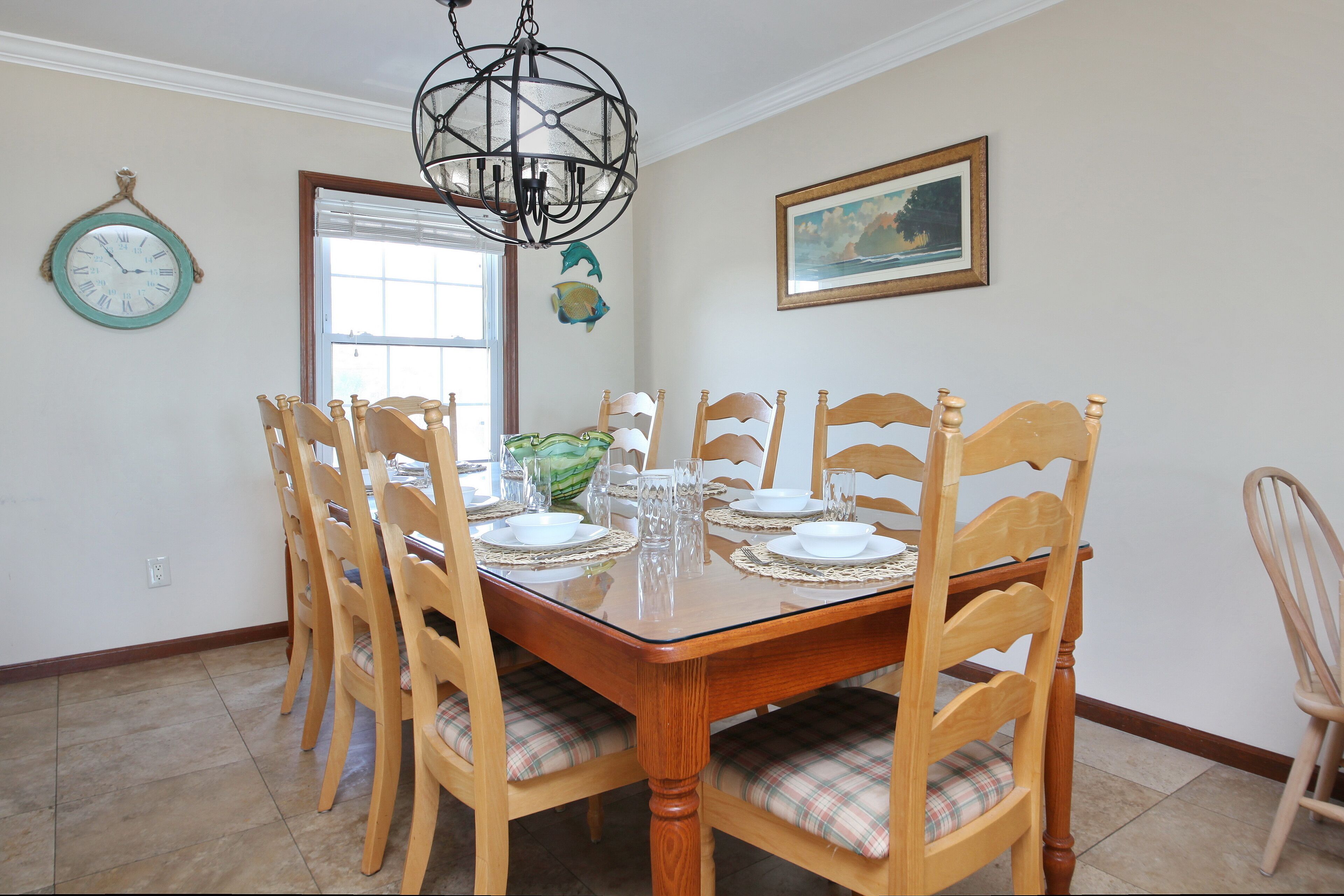 Comedor con una mesa de madera dispuesta para seis personas, rodeada por seis sillas de madera con cojines de cuadros.