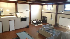 A spacious living area with a pool table, a sofa, a dining table with chairs, and a kitchen area with a refrigerator and a microwave. - Knights of Pythias Loft Downtown Albany, Oregon 2400 Sq Ft Of Space (ALBANY)