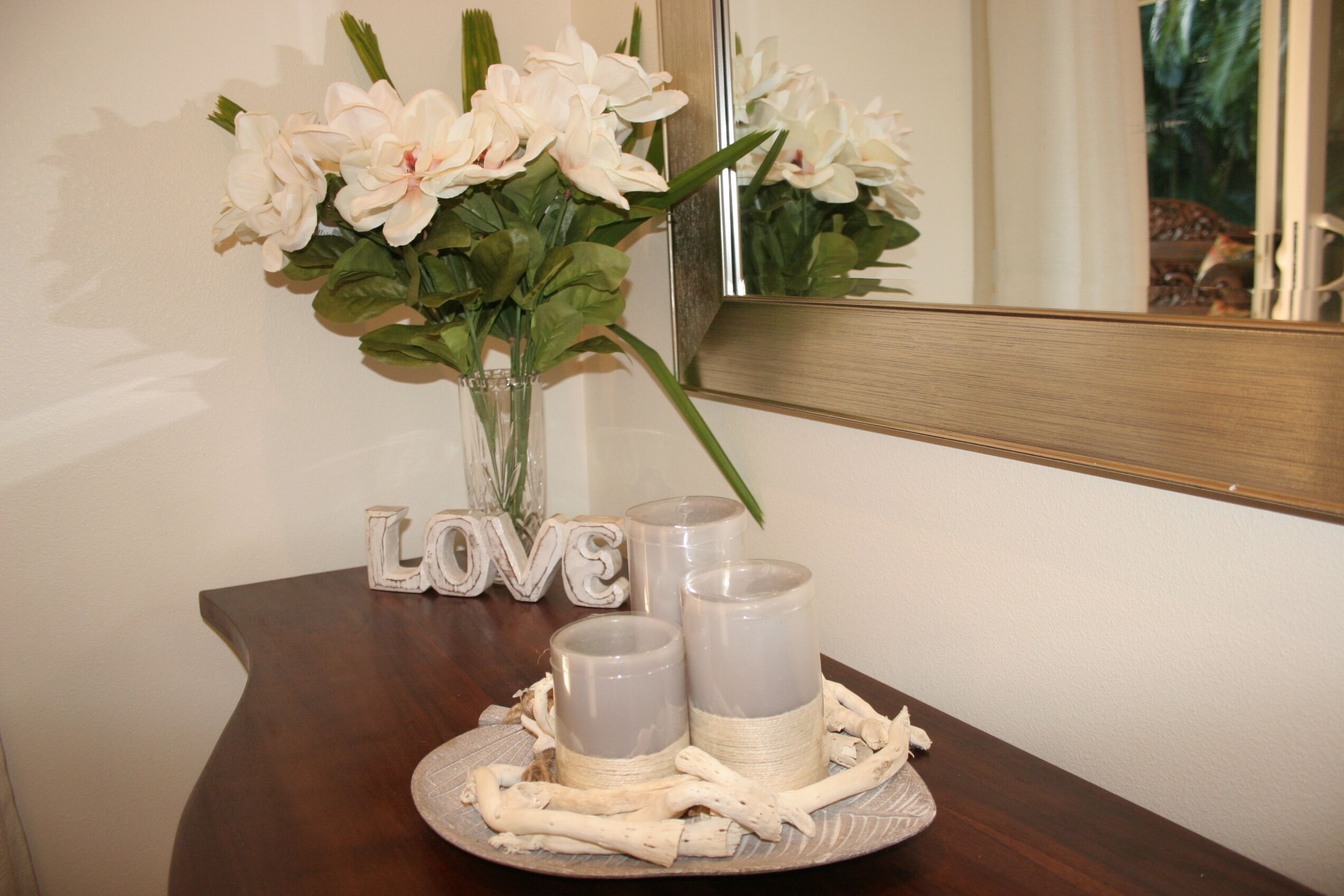 Een tafel met een bloevas, kaarsen en het woord 'LOVE' als decoratie.