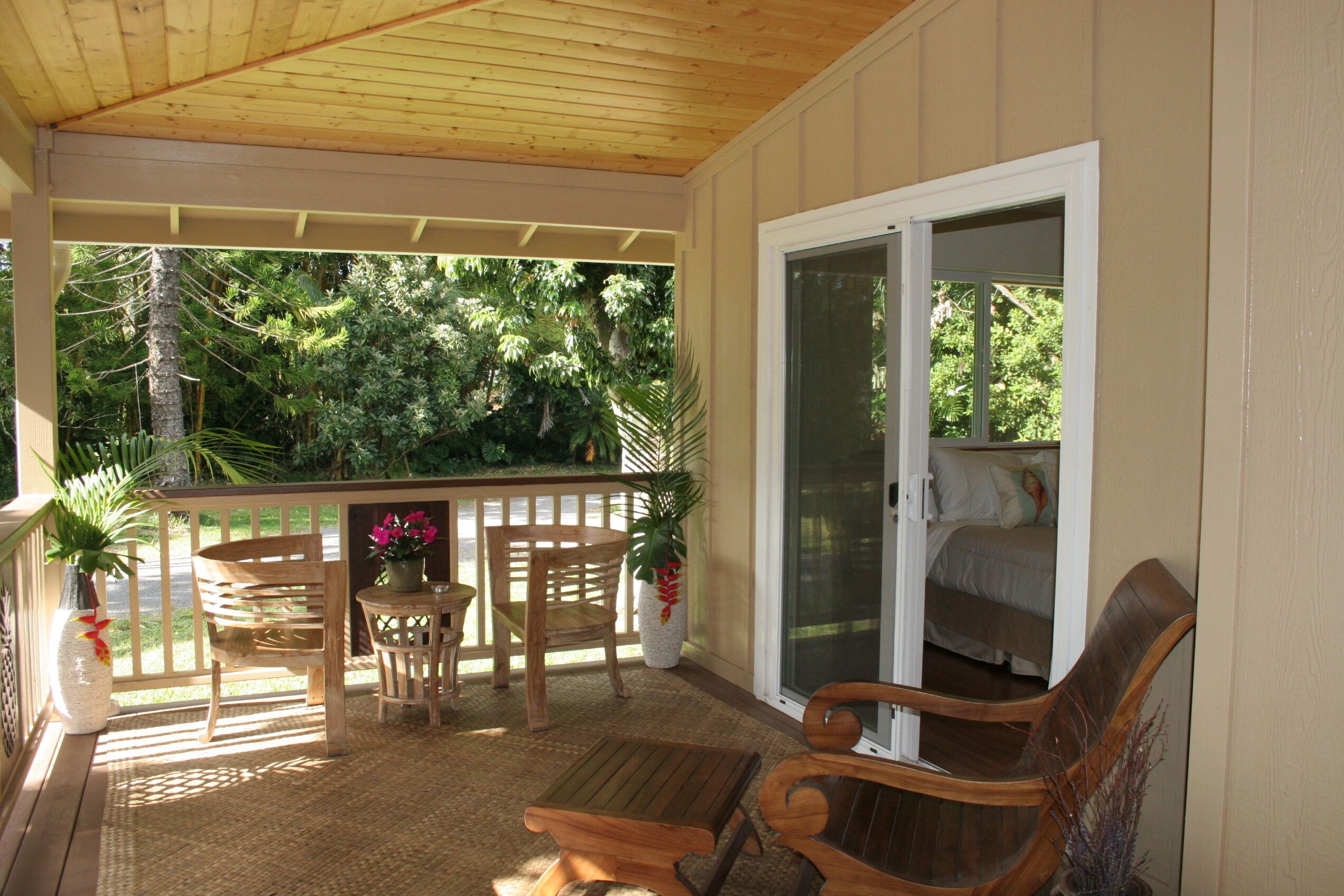 A covered porch with wooden furniture, a small table, and chairs.