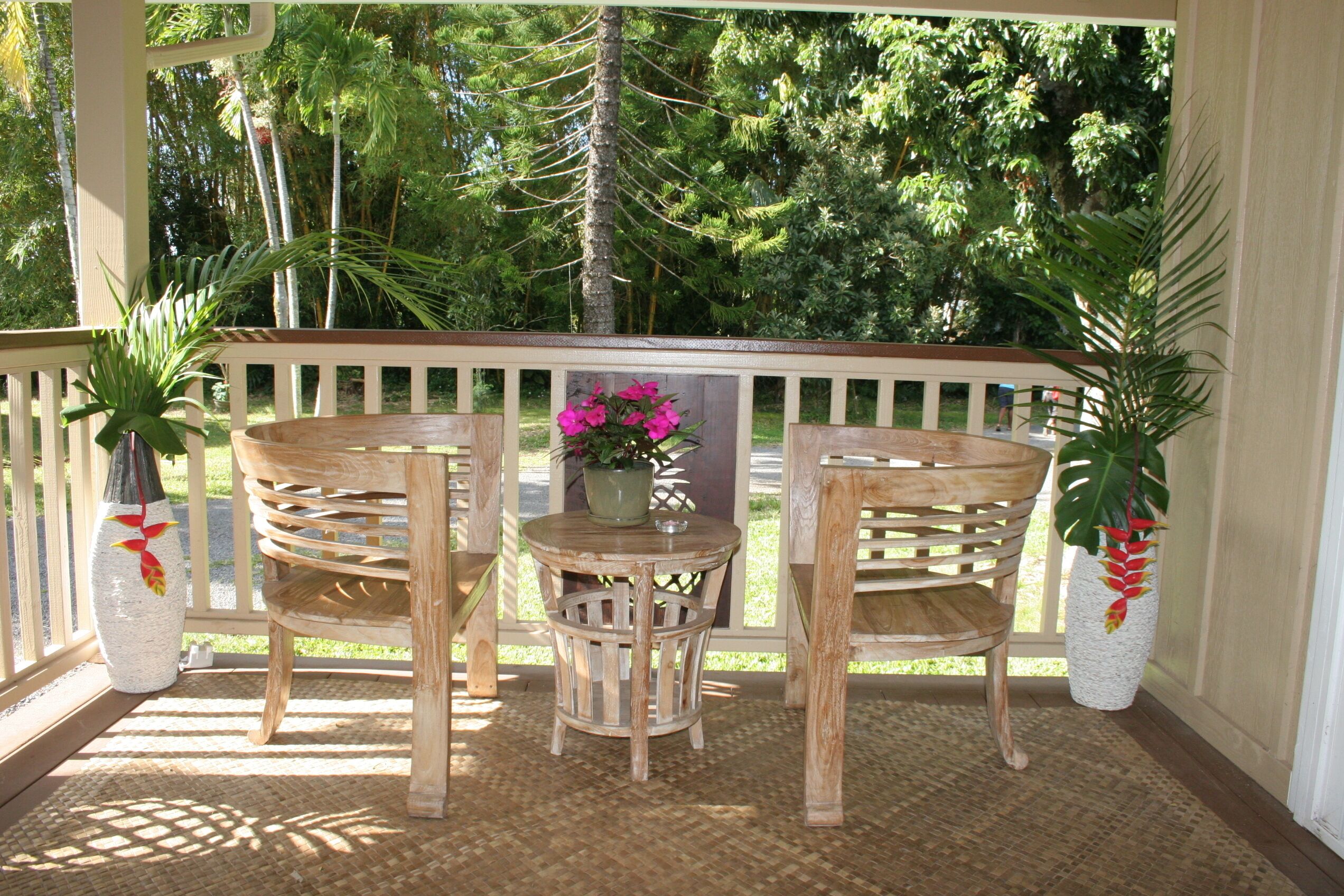 Une terrasse en bois avec deux chaises et une table, entourée de plantes en pot.