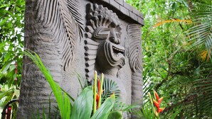 A stone structure with carved wings and a face, surrounded by lush tropical plants. - *Peace and Serenity* (Haiku)