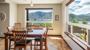 A dining area with a large table and chairs, a view of mountains and a lake, and a balcony with a railing. - Luxury Condo / Incredible Views Pool / Spas (Manson)