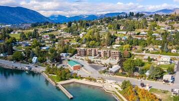 An aerial view of a coastal town with residential buildings, a marina, and mountains in the background.
