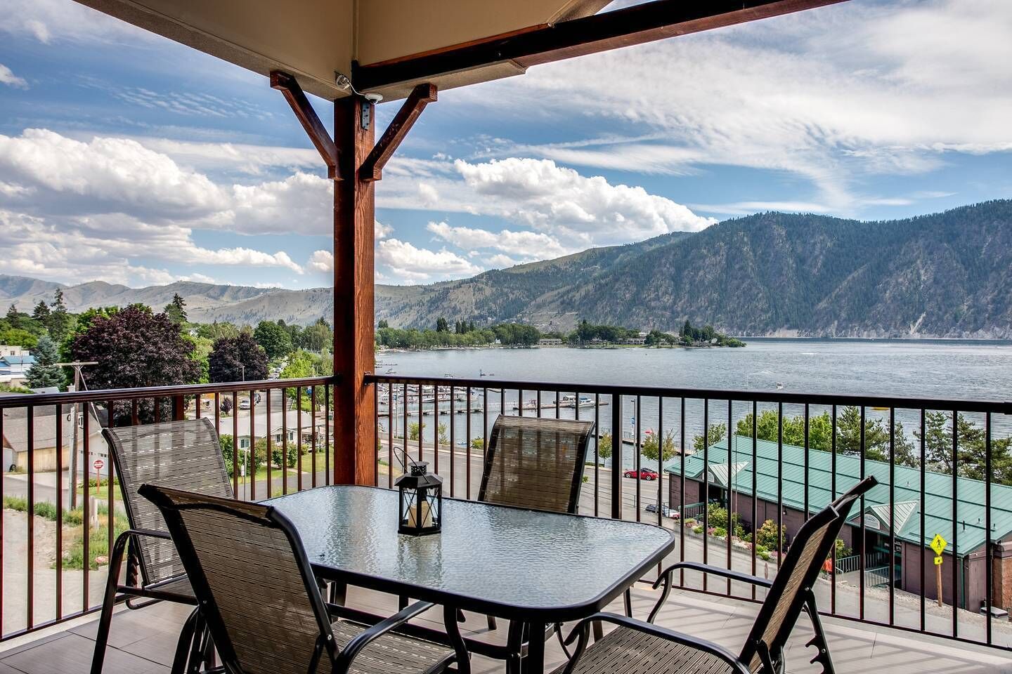 A balcony with a table and chairs, overlooking a lake and mountains.