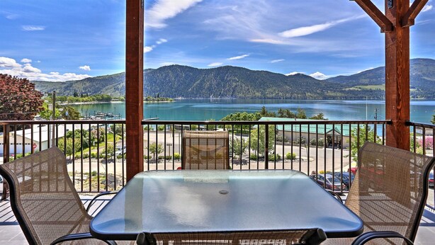 A balcony with a table and chairs, overlooking a lake and mountains. - Luxury Condo / Incredible Views Pool / Spas (Manson)