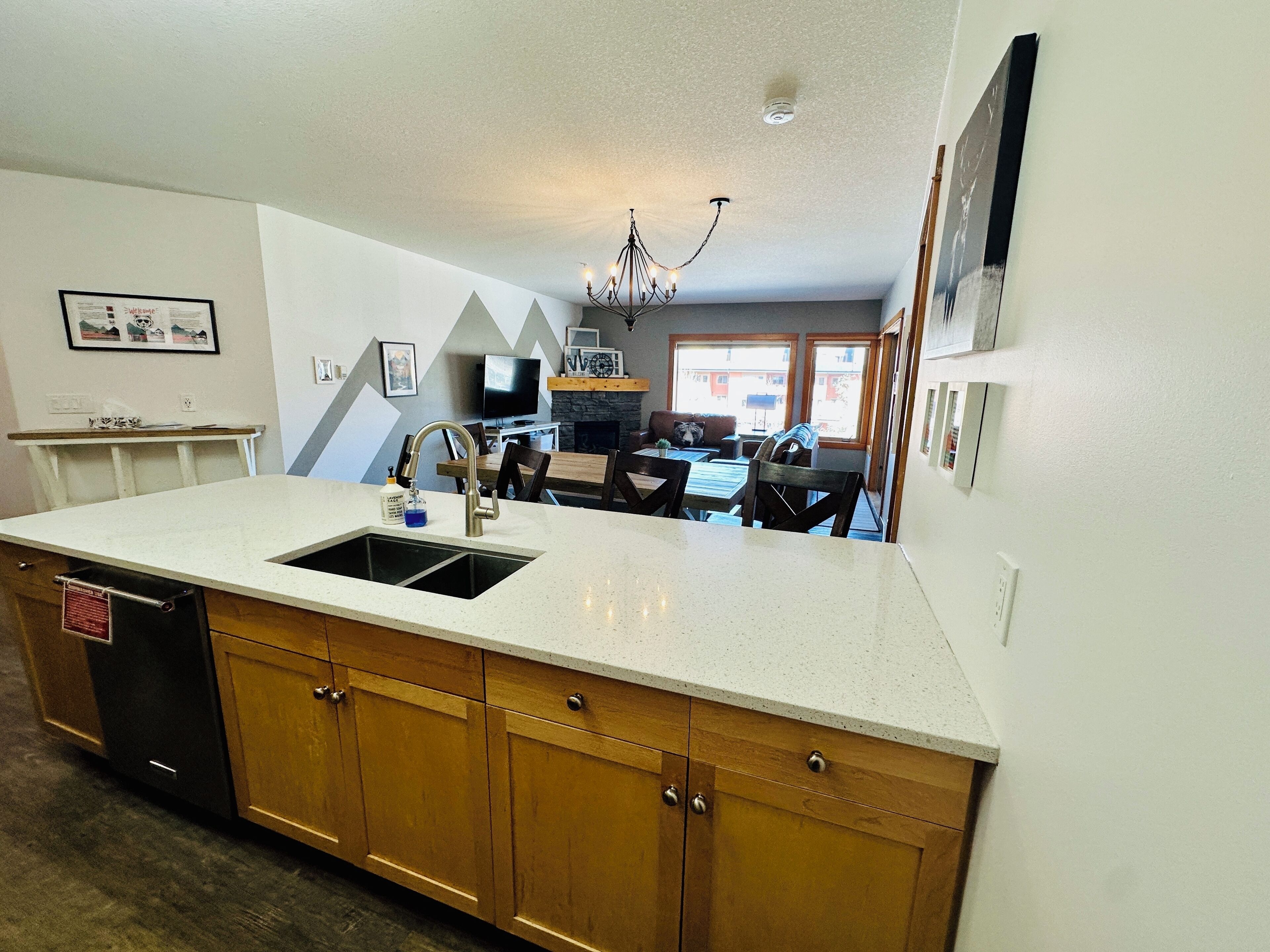 A kitchen with a large island, wooden cabinets, and a built-in dishwasher.