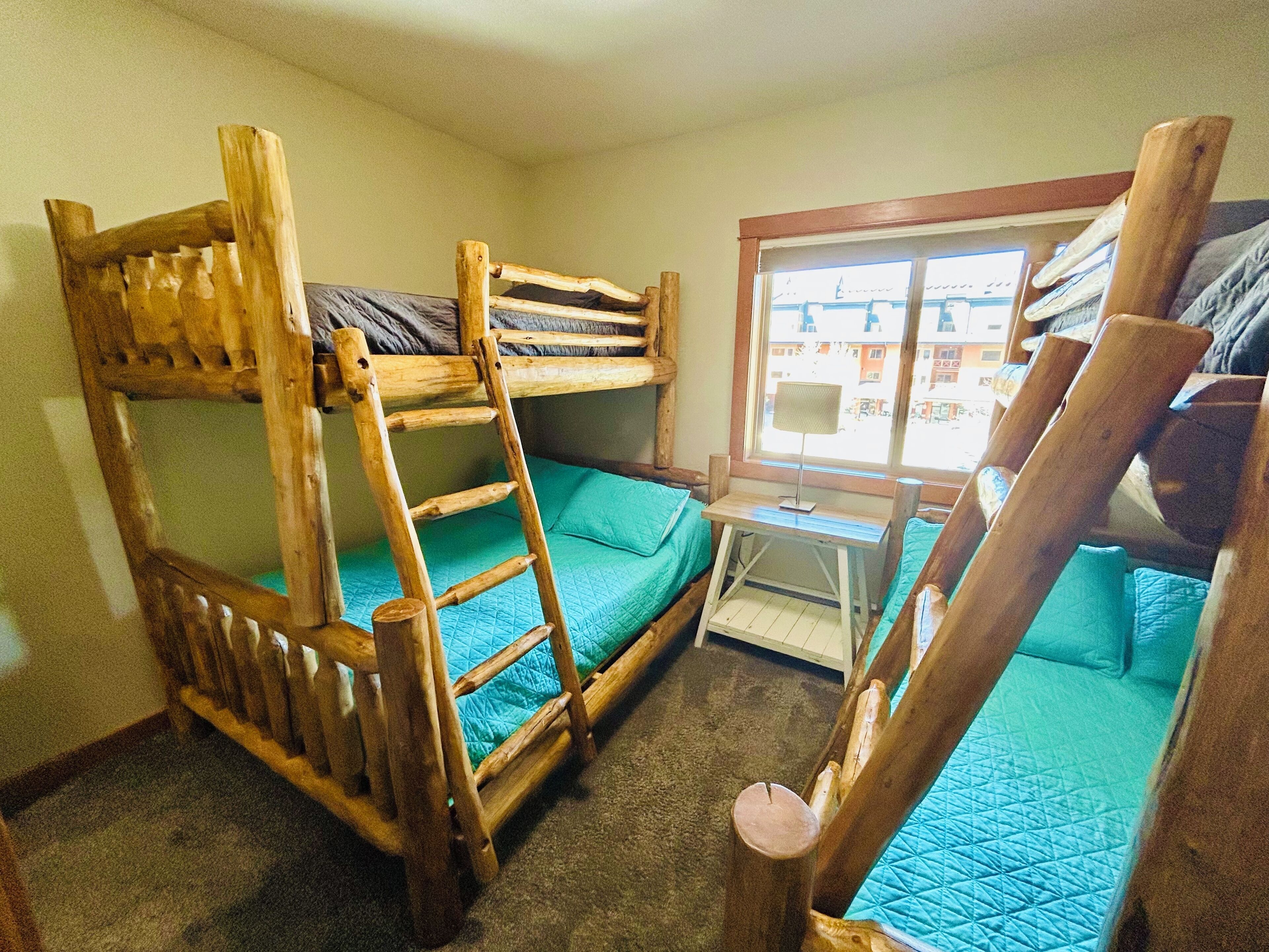 Une chambre avec un lit superposé, une fenêtre et un bureau.