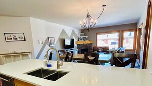 A modern kitchen with a large island, a dining area, and a fireplace.