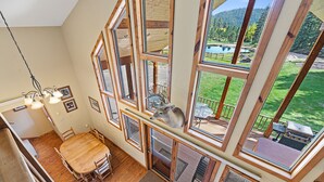 A multi-level room with a dining area, large windows, and a view of a lake and forest. - Large private lot.  Beautiful cabin with a stream and trout pond!  (Lead)