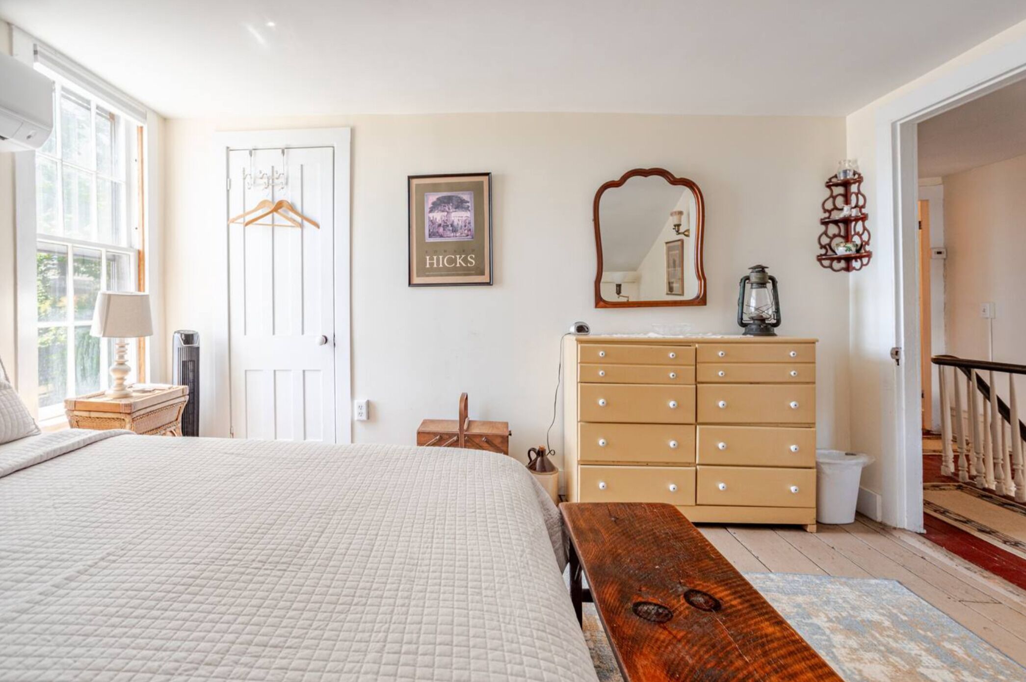 A bedroom with a bed, dresser, and a mirror.