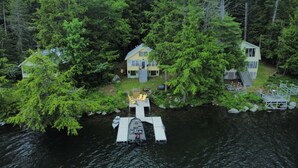 Un chalet au bord du lac, doté d’un quai, et entouré d’une forêt dense.