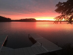 A dock extending into calm water with a sunset in the background.