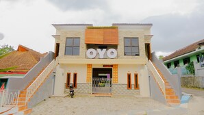 A two-story building with a sign reading "OYO" and a staircase leading to the entrance. - Hotel O Queen Homestay (Batu)