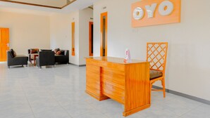 A reception area with a wooden desk, a reception counter, and a chair with a lattice backrest. - Hotel O Queen Homestay (Batu)