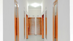A corridor with wooden doors and white walls. - Hotel O Queen Homestay (Batu)