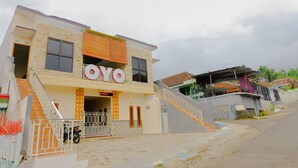 A building with a prominent 'YO' sign, a staircase leading to the entrance, and a gated parking area. - Hotel O Queen Homestay (Batu)