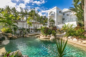 A resort with a clear pool, palm trees, and a white building with balconies. - Poolside Apt In Alamanda Beachfront Resort 55 (Palm Cove)