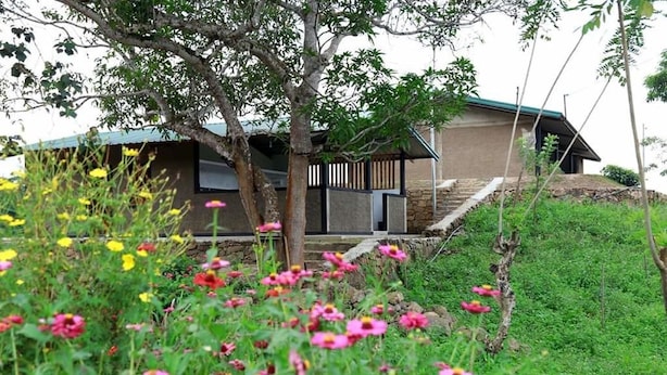 A modern house with a sloped roof, surrounded by a garden with various flowers. - Mount K Resort - Hostel (Kahawatta)