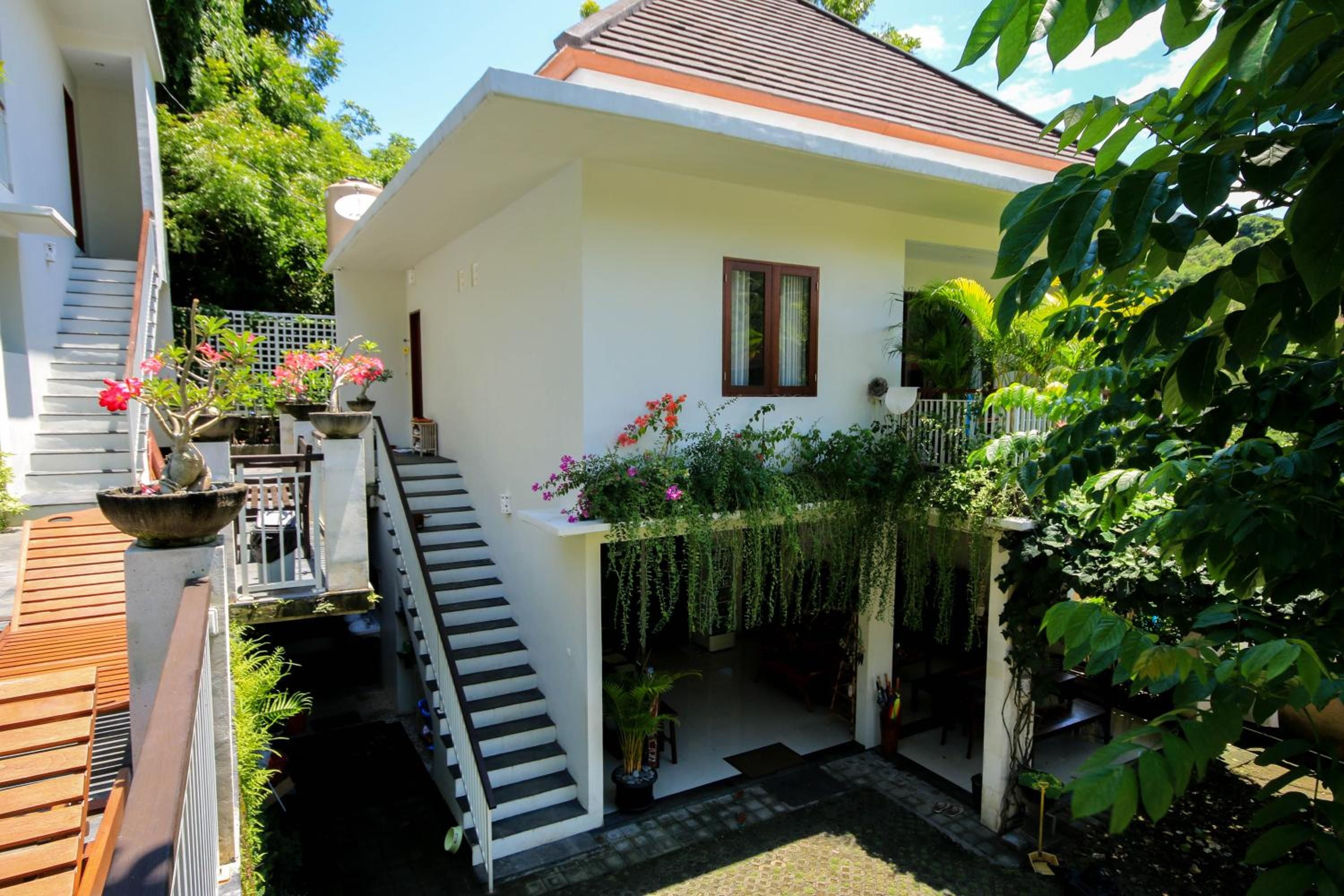 A two-story house with a staircase, outdoor seating, and potted plants.