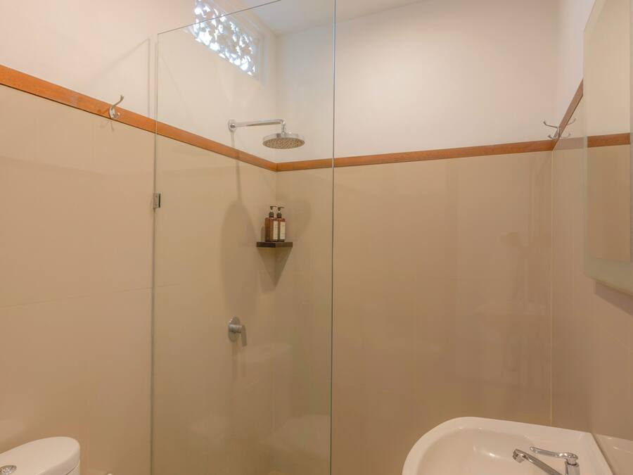 A modern bathroom with a glass-enclosed shower, a white sink, and a toilet.