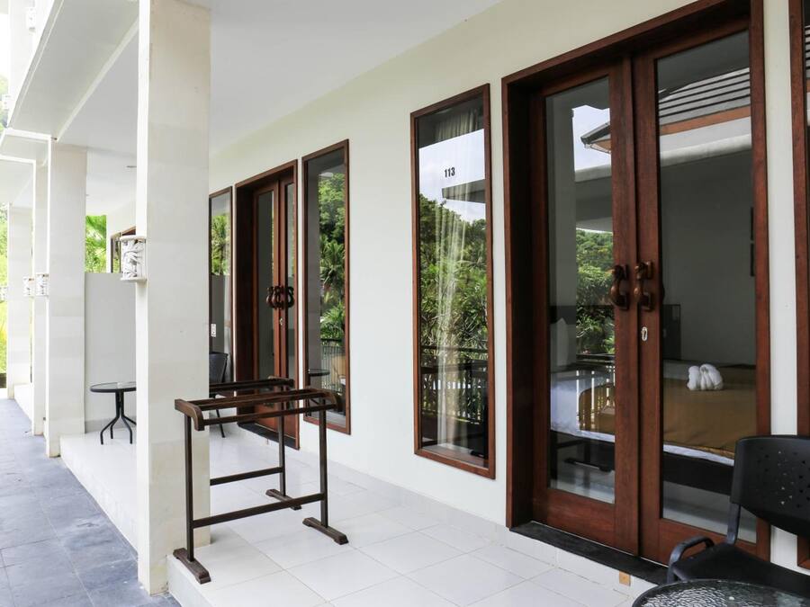 A hotel entrance with large glass doors, a small table, and a chair outside.