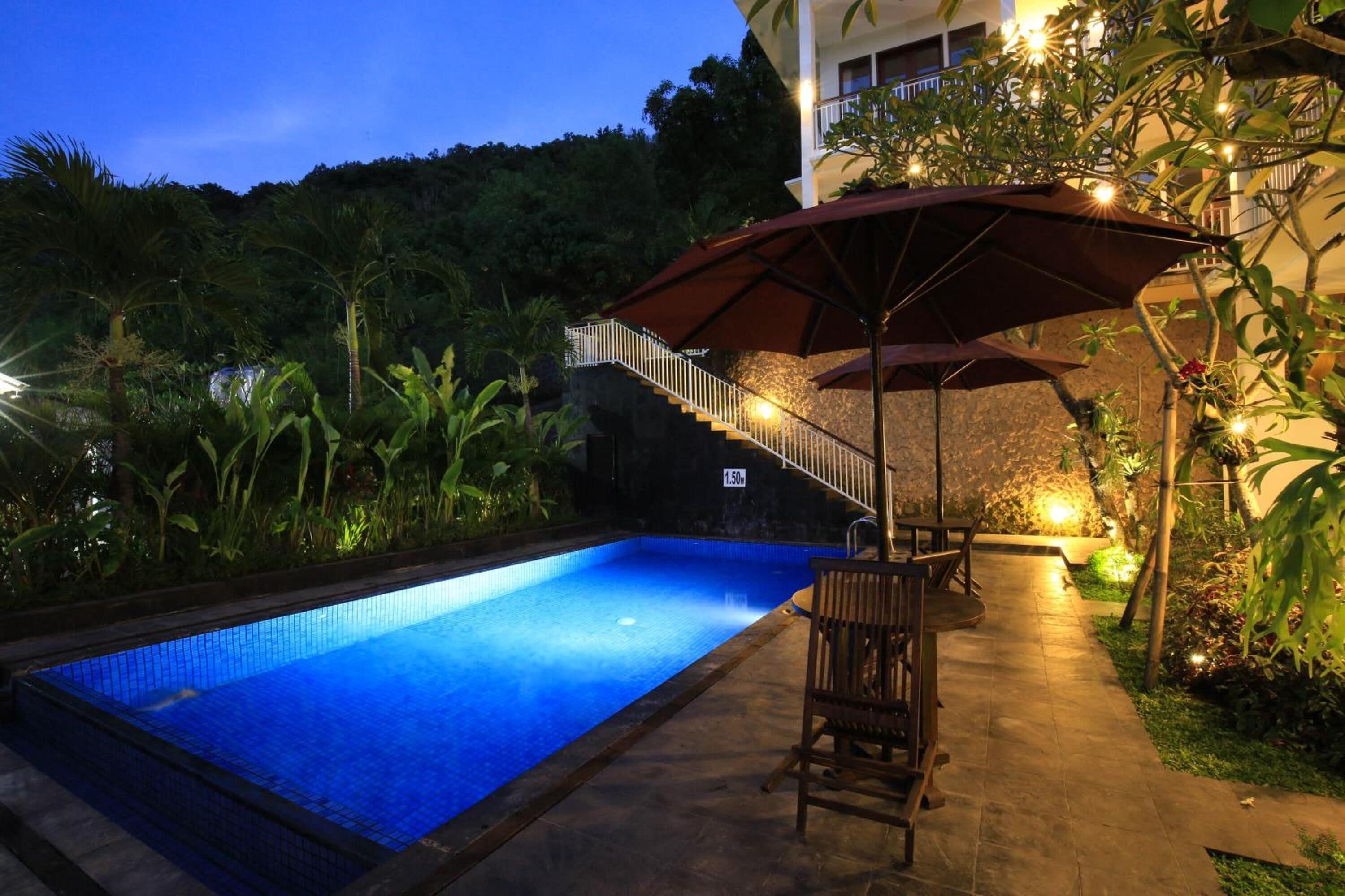 Ein Pool mit einer gefliesten Kante, ein Holzstuhl und eine Treppe, die zu einem Balkon führt.