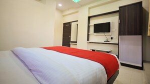 Ein Hotelzimmer mit einem Bett, einem an der Wand montierten Fernseher und einem Kleiderschrank.
