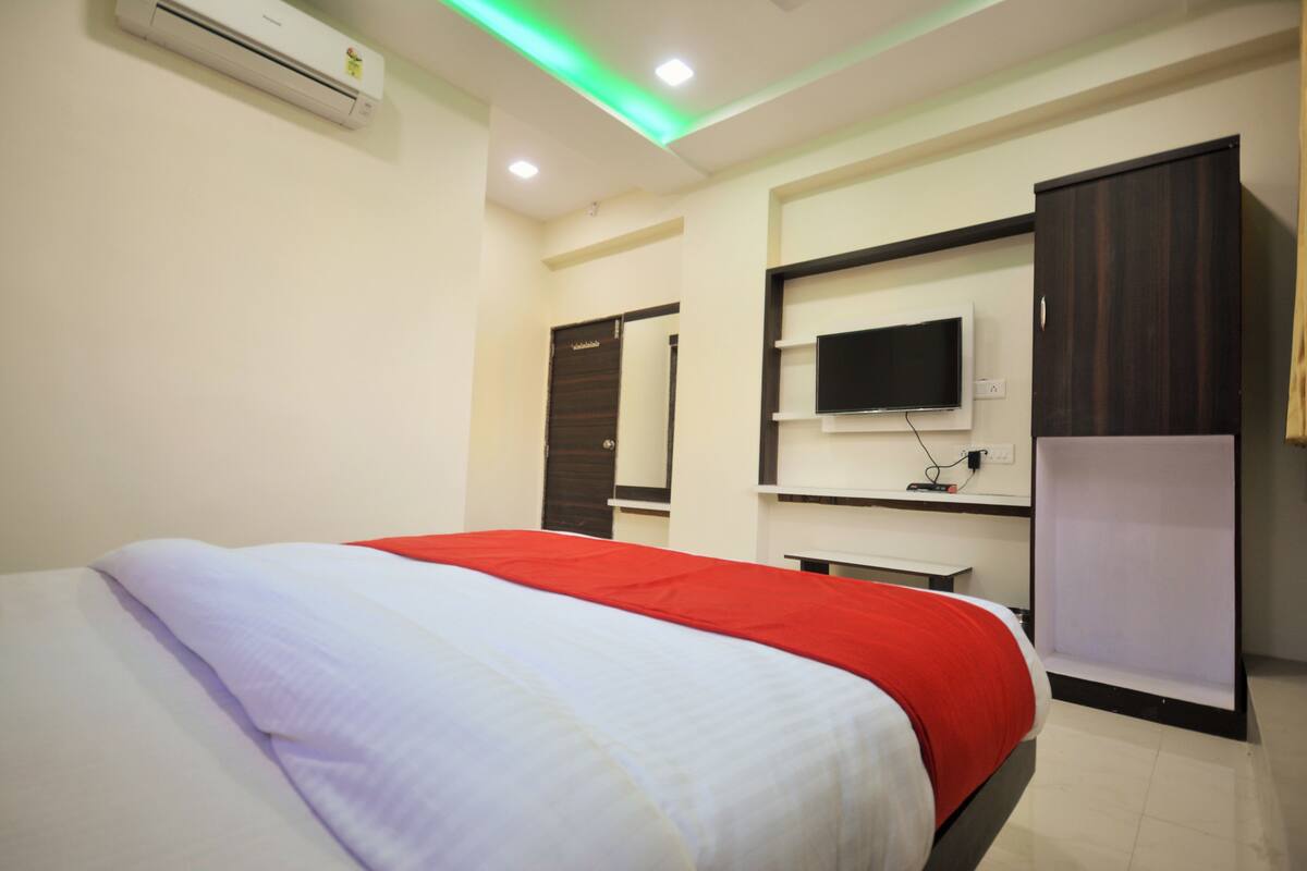 A hotel room with a bed, a TV mounted on the wall, and a wardrobe.