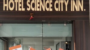 Der Eingang des Hotel Science City Inn mit einem Schild und drei indischen Flaggen.