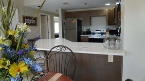 A kitchen with a central island, a dining table with chairs, and a vase of flowers. - City View 411 3BD Condo with Fireplace by RedAwning (Pigeon Forge)