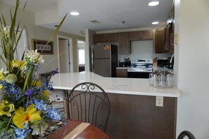 A kitchen with a central island, a dining table with chairs, and a vase of flowers. - City View 411 3BD Condo with Fireplace by RedAwning (Pigeon Forge)