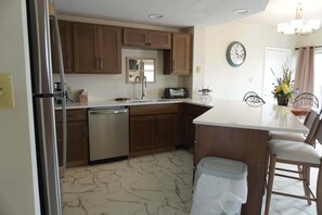 Eine Küche mit Holzausstattung, einer Spülmaschine, einem Spülbecken, einem Toaster und einer Uhr an der Wand.